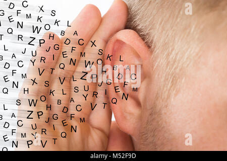 Homme tenant la main près de l'oreille et l'écoute particulière Lettres Alphabet Fly Banque D'Images