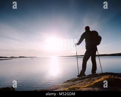 Silhouette de l'homme seul à la dynamique vers le coucher du soleil. Flare et reflétée dans les eaux peu profondes du niveau de la mer Banque D'Images