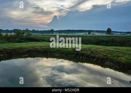 Paysage du village avec un étang et des traînées de brume en Pologne Banque D'Images