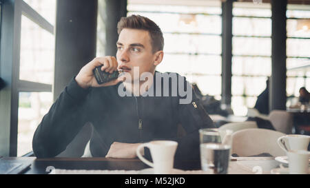 Jeune homme vaping en espace public fermé.fumer cigarette électronique dans cafe.La dépendance à la nicotine.moyen pour cesser de fumer,vieille habitude.Vaping aroma,urbain man u Banque D'Images