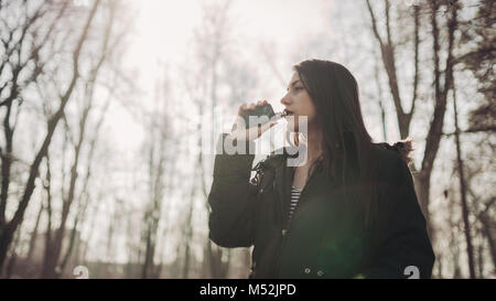 Jeune femme à l'aide de la cigarette électronique pour fumer dans les lieux publics.restriction fumée,interdiction de fumer.En utilisant l'appareil avec des liquides aromatisés vaping.E-juice vapin Banque D'Images