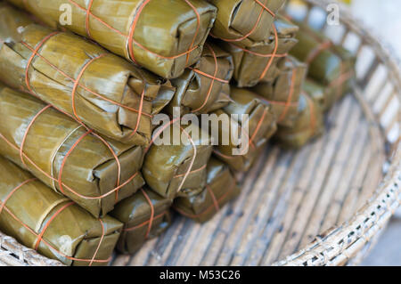 Close up les bananes avec le riz collant pack sur bois en osier panier de marché, Khao Tom la boue, l'arrière-plan flou Banque D'Images