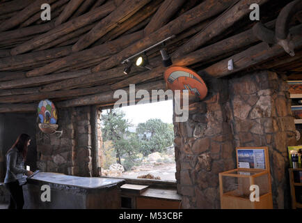 Symposium sur l'histoire du Grand Canyon Desert View Watchtower . En vue de l'information aux visiteurs Kiva Room 24, CMA, don des poutres au plafond, circulaire et Hopi Boucliers sur les murs. [Brown poutres plafond circulaire robuste créer au-dessus de la grande baie vitrée derrière le bureau d'information aux visiteurs, un visiteur est debout à la recherche d'informations sur au dessus du bureau ; deux boucliers colorés Hopi sont attachés à des murs d'appliques monté sur chaque côté de la fenêtre.] Le Grand Banque D'Images