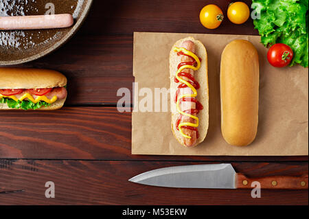 Délicieux avec de la saucisse à hot-dog, tomates, salade, et le couteau de mise à plat sur fond de bois. Vue d'en haut. Banque D'Images