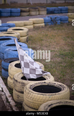 Pavillon de course, jaune et bleu sur le parquet de pneus race course. Banque D'Images