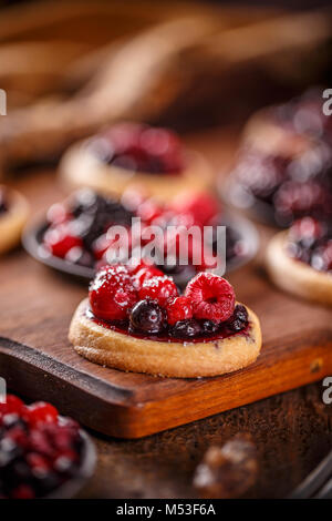 Close up de mini tartelettes aux fruits frais parti sur fond de bois Banque D'Images