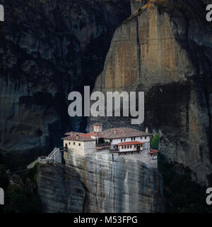 Rousanou Monastère (météores, Grèce) au lever du soleil, avec des falaises de couleur sombre à l'arrière du terrain Banque D'Images