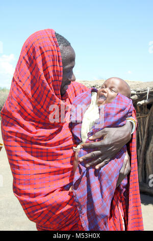 Les Masais père exerçant son enfant dans ses bras, l'aire de conservation de Ngorongoro, en Tanzanie. Banque D'Images