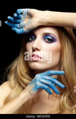 Jeune femme blonde aux cheveux longs et les mains peintes en bleu peinture Banque D'Images