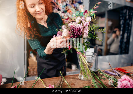 Mettre des fleurs femelles winsome en vase de la boutique de fleuriste Banque D'Images