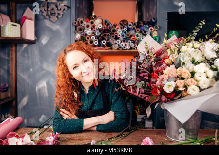 Fleuriste designer avec les cheveux rouges et les yeux verts qui travaillent à l'atelier du fleuriste Banque D'Images