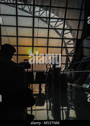 En attendant les touristes pour le vol du matin à l'aéroport d'embarquement et ils regardant à travers la vitre pour voir la belle de lever du soleil. Soleil dans la mor Banque D'Images