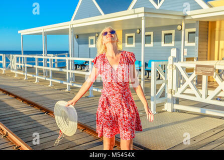 Femme blonde insouciante jouit de la lumière au coucher du soleil sur la célèbre jetée en bois à Busselton Busselton, Australie de l'Ouest. La liberté de voyage australienne. Woman en lieu emblématique. Banque D'Images