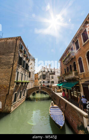 La belle ville d'itinéraires vénitiens du canal et des promenades en gondole, le soleil flair dans le coin avec les bâtiments de la vieille ville en face. Banque D'Images