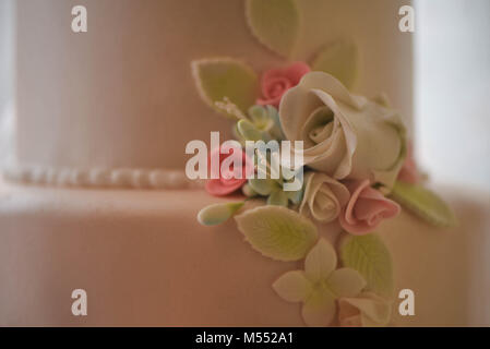 Fermer l'alimentation à la main des belles fleurs glacé sur un gâteau de mariage Banque D'Images