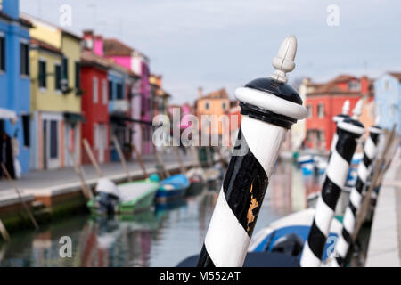 Scène de rue typique en noir et blanc bollards en premier plan et peint de couleurs vives, maisons en arrière-plan, à Burano, Venise, Italie Banque D'Images