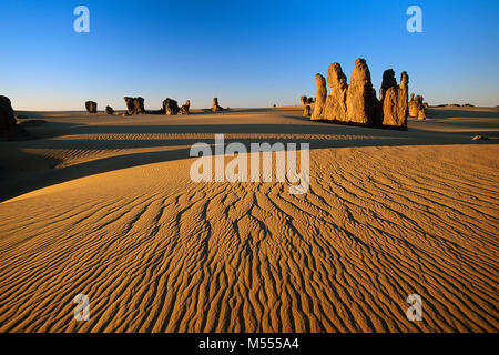 L'Algérie. Près de Tamanrasset. Le Tassili du Hoggar. Désert du Sahara. Dunes de sable et rochers sur fond de ciel bleu. Banque D'Images