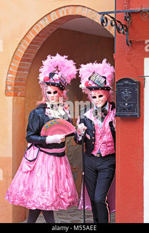 Un couple de gens costumés dans une étroite rue colorée pendant le Carnaval de Venise (Carnevale di Venezia) à Burano (Venise), Italie Banque D'Images