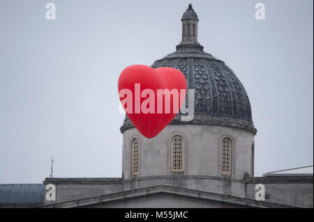 Trafalgar Square, Londres, Royaume-Uni. 20 février 2018. Le créateur de mode britannique d'Anya Hindmarch, projet public de design Chubby Coeurs, voit un cœur rouge gonflable géant voler au-dessus de Trafalgar Square sur un matin gris et pluvieux. Credit : Malcolm Park/Alamy Live News. Banque D'Images