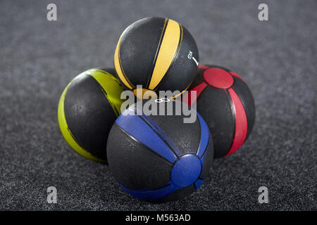 Les medicine-balls colorés sur le plancher du gymnase Banque D'Images