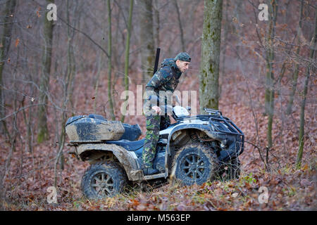 Jeune chasseur sur un quad à la recherche de jeu dans la forêt Banque D'Images