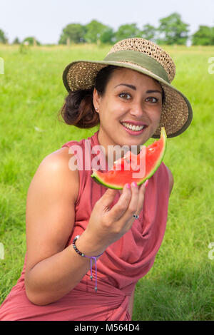 Woman wearing hat mange le melon frais à l'extérieur Banque D'Images