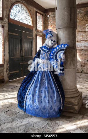 Masque de femme en costume bleu et très décoratif debout à côté de pilier en vieux, salle vide pendant le Carnaval de Venise (Carnaval de Venise). Banque D'Images