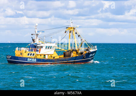 Un bateau de pêche quitte le port et met les voiles sur les lieux de pêche. Banque D'Images