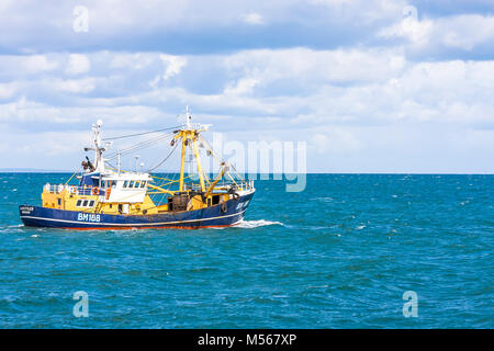 Un bateau de pêche quitte le port et met les voiles sur les lieux de pêche. Banque D'Images