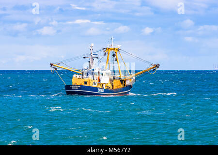 Un bateau de pêche quitte le port et met les voiles sur les lieux de pêche. Banque D'Images