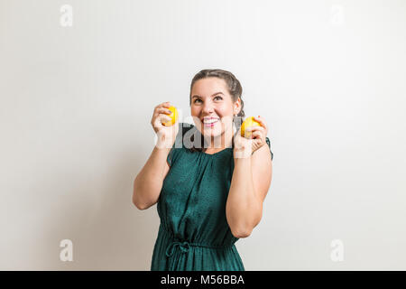 Belle jeune fille sourit debout sur fond blanc est titulaire d'un citrons Banque D'Images