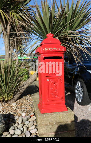 Cute Mini rouge vif post Box (boîte) dans un pilier de la côte sud de l'Angleterre au soleil Banque D'Images