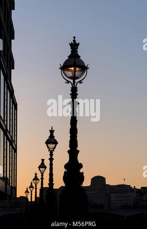 La ligne de l'atmosphère de l'élégant lampadaire lights silhouette sur un ciel clair au coucher du soleil avec des bâtiments Banque D'Images