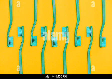 Contexte minimaliste avec des brosses à dents verte dans la rangée, isolé sur fond jaune