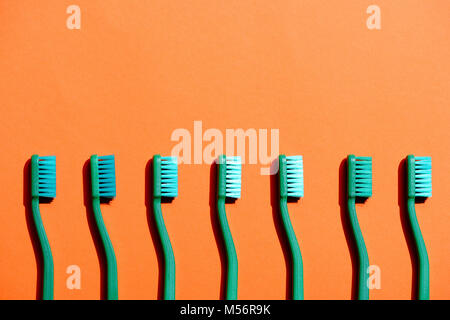 Brosses à dents verte dans la rangée, sur l'orange with copy space