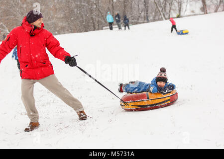 Image de l'homme roulant son fils le jour de l'hiver Banque D'Images