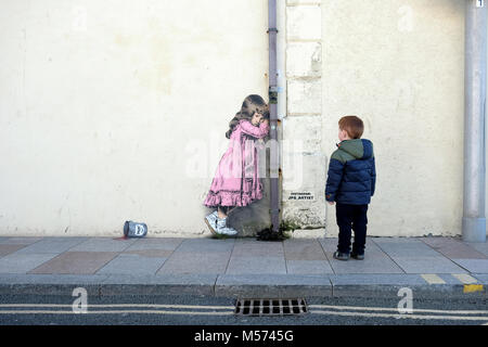 Un jeune garçon regarde un graffiti de style banksy d'une jeune fille criant sur une boîte de peinture renversée. L'œuvre de JPS et intitulée a déversé l'anarchie Banque D'Images