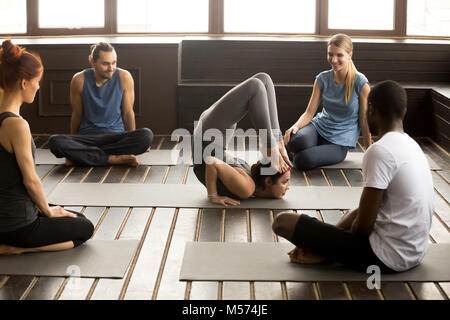 Les personnes à la recherche d'instructeur multiraciale au yoga à poser Banque D'Images