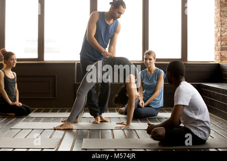 Enseignant de sexe masculin assisting woman doing yoga exercice sur tapis bridge Banque D'Images