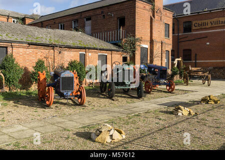 Un affichage de trois tracteurs Fordson vintage et un panier de roue en bois à l'extérieur du village restaurant Chili, Northampton UK Banque D'Images