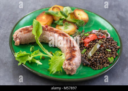 France La saucisse de Toulouse grillée avec potatoaes rôti et salade et lentilles sur le vieux fond de bois Banque D'Images