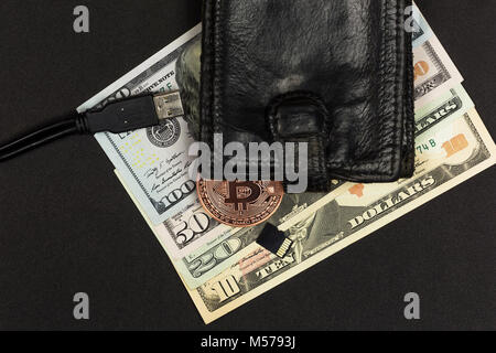 Sur un fond sombre se trouve un porte-monnaie avec l'argent comptant, Bitcoin, un lecteur flash et un connecteur USB Banque D'Images