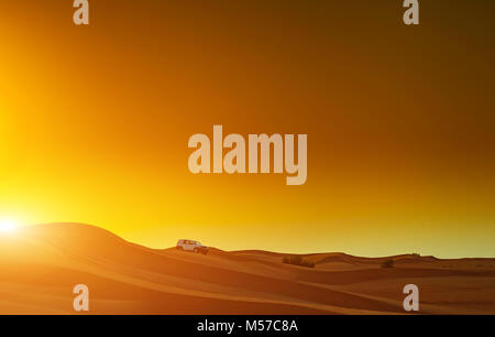 Camion hors route ou d'un vus à cheval dans les dunes du désert arabique au coucher du soleil. Le tout-terrain a été modifié pour être reconnus. Banque D'Images