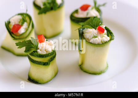 Rouleaux de courgettes farcies au fromage et ciboulette et paprika rouge. Banque D'Images