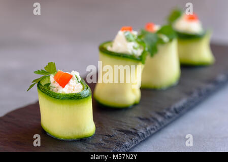 Rouleaux de courgettes farcies au fromage et ciboulette et paprika rouge. Banque D'Images