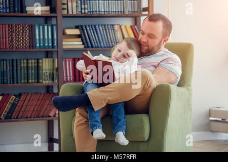 Photo de daddy lecture livre à son sitting in chair Banque D'Images