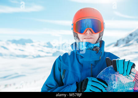 Portrait de l'homme sportif dans helmet looking at camera with snowboard sur fond de snowy hill Banque D'Images