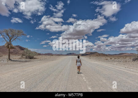 Jeune fille qui marche sur la route de gravier désert de Namibie. Banque D'Images