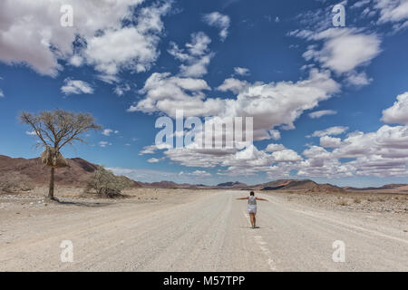 Jeune fille qui marche sur la route de gravier désert de Namibie. Banque D'Images