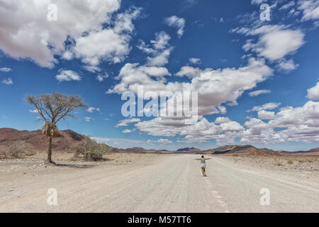 Jeune fille qui marche sur la route de gravier désert de Namibie. Banque D'Images